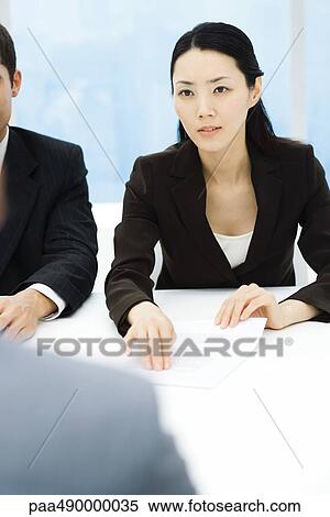 Business associates in meeting, businesswoman holding out document, looking across table View Large Photo Image Stock Photography - Business associates in meeting, businesswoman holding out document, looking across table. Fotosearch