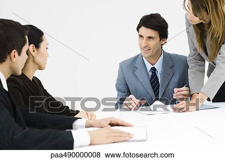 Business associates sitting at table, one man signing document View Large Photo Image Stock Photo - Business associates sitting at table, one man signing document. Fotosearch