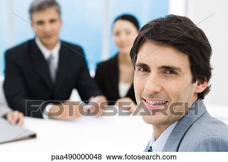 Businessman in meeting, smiling at camera View Large Photo Image Stock Photo - Businessman in meeting, smiling at camera. Fotosearch