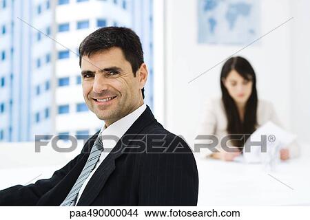 Businessman in office, smiling at camera, portrait View Large Photo Image Picture - Businessman in office, smiling at camera, portrait. Fotosearch