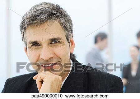 Stock Image - Businessman, portrait, colleagues standing in background. Fotosearch
