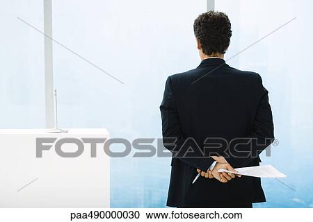 Stock Image - Businessman preparing to give speech, looking out of window. Fotosearch