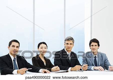 Group of business associates seated at table, looking at camera View Large Photo Image Stock Image - Group of business associates seated at table, looking at camera. Fotosearch