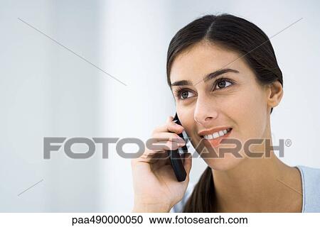 Young woman using cell phone, smiling View Large Photo Image Stock Image - Young woman using cell phone, smiling. Fotosearch