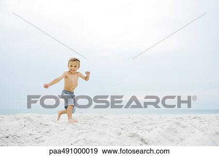 Little boy running at the beach, smiling at camera View Large Photo Image Stock Photo - Little boy running at the beach, smiling at camera. Fotosearch
