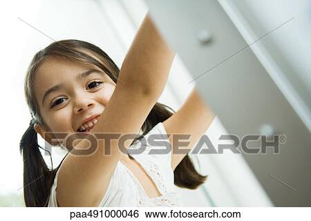 Little girl with pigtails smiling at camera, arms raised, portrait View Large Photo Image Stock Photograph - Little girl with pigtails smiling at camera, arms raised, portrait. Fotosearch