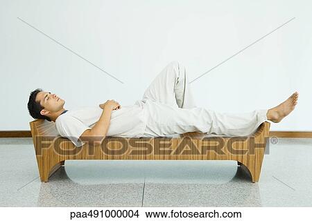 Man lying on bench with eyes closed, side view View Large Photo Image Picture - Man lying on bench with eyes closed, side view. Fotosearch
