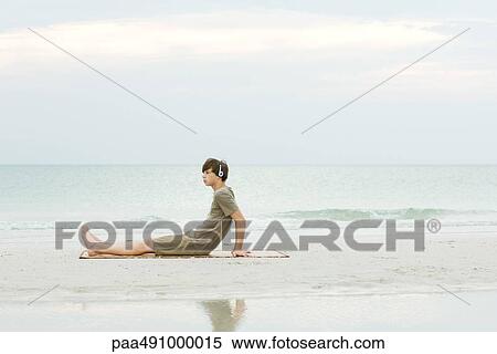 Teenage boy sitting on the beach, listening to headphones, side view View Large Photo Image Stock Photography - Teenage boy sitting on the beach, listening to headphones, side view. Fotosearch
