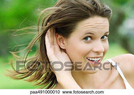 Teenage girl holding hand next to ear, looking sideways at camera, smiling, close-up View Large Photo Image Stock Image - Teenage girl holding hand next to ear, looking sideways at camera, smiling, close-up. Fotosearch