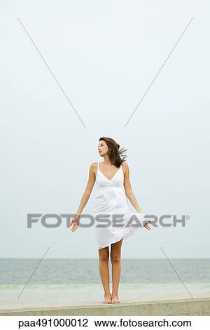 Teenage girl in sundress standing at the beach, tousled by wind, eyes closed View Large Photo Image Stock Image - Teenage girl in sundress standing at the beach, tousled by wind, eyes closed. Fotosearch