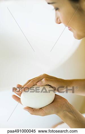 Stock Photography - Woman holding bar of soap in hands, looking down, cropped view. Fotosearch