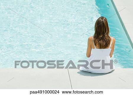 Woman sitting on edge of swimming pool, rear view, high angle View Large Photo Image Picture - Woman sitting on edge of swimming pool, rear view, high angle. Fotosearch