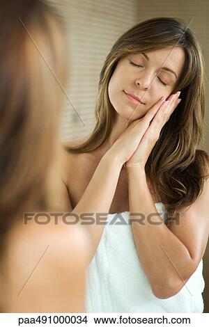 Woman standing in front of mirror with eyes closed, head resting on clasped hands, smiling View Large Photo Image Picture - Woman standing in front of mirror with eyes closed, head resting on clasped hands, smiling. Fotosearch