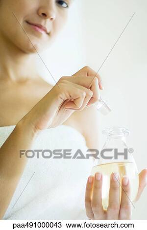 Woman wrapped in towel opening perfume bottle, smiling at camera, cropped view View Large Photo Image Stock Image - Woman wrapped in towel opening perfume bottle, smiling at camera, cropped view. Fotosearch
