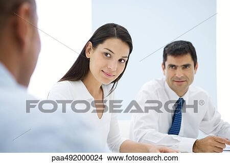 Business associates having meeting, focus on young woman in middle ground View Large Photo Image Picture - Business associates having meeting, focus on young woman in middle ground. Fotosearch