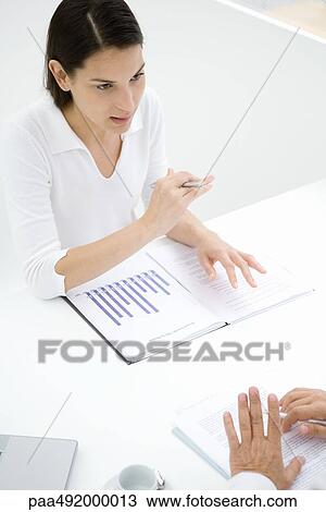 Stock Image - Business colleages sitting across table from each other, talking and gesturing. Fotosearch