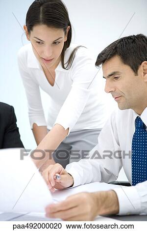 Businessman and female assistant looking at document together View Large Photo Image Stock Image - Businessman and female assistant looking at document together. Fotosearch