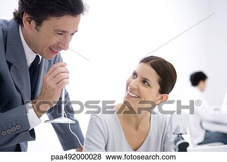 Businessman holding microphone while female colleague watches View Large Photo Image Stock Photo - Businessman holding microphone while female colleague watches. Fotosearch
