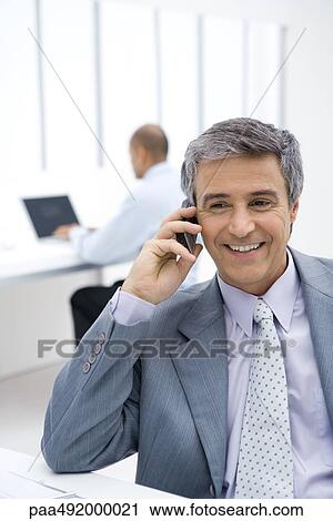 Businessman using cell phone in office View Large Photo Image Stock Image - Businessman using cell phone in office. Fotosearch