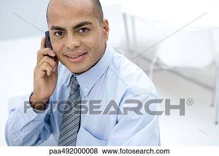 Businessman using cell phone, smiling at camera View Large Photo Image Stock Photo - Businessman using cell phone, smiling at camera. Fotosearch