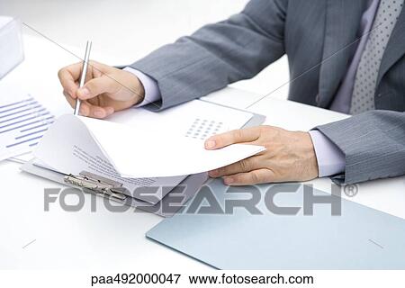 Businessman working at desk, cropped view View Large Photo Image Stock Photo - Businessman working at desk, cropped view. Fotosearch