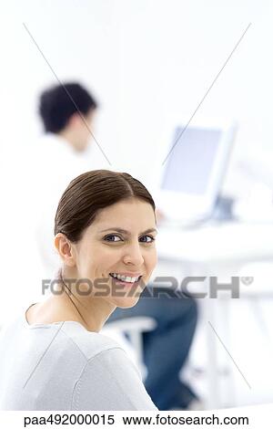 Female office worker, smiling over shoulder at camera View Large Photo Image Stock Photography - Female office worker, smiling over shoulder at camera. Fotosearch