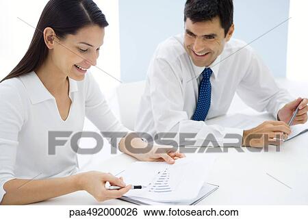 Two business associates studying graph together, smiling View Large Photo Image Stock Photograph - Two business associates studying graph together, smiling. Fotosearch