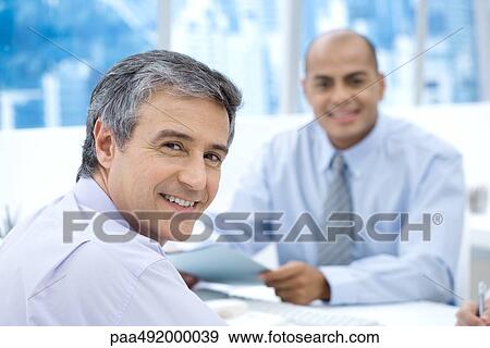 Two businessmen in office, smiling at camera View Large Photo Image Stock Photo - Two businessmen in office, smiling at camera. Fotosearch