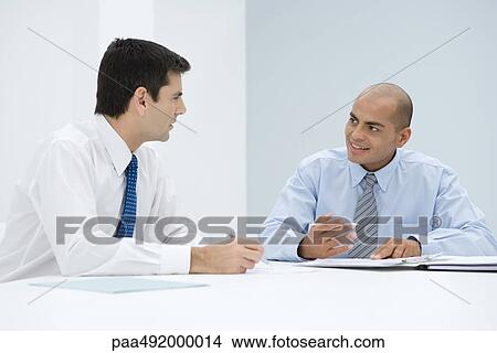 Picture - Two businessmen sitting at table having meeting. Fotosearch