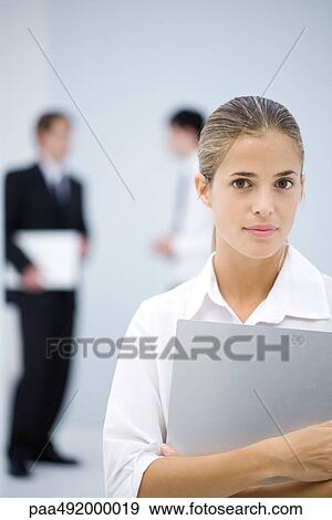 Young businesswoman holding file, looking at camera View Large Photo Image Stock Photo - Young businesswoman holding file, looking at camera. Fotosearch