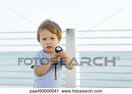 Little boy holding flashlight, frowning at camera View Large Photo Image Stock Image - Little boy holding flashlight, frowning at camera. Fotosearch