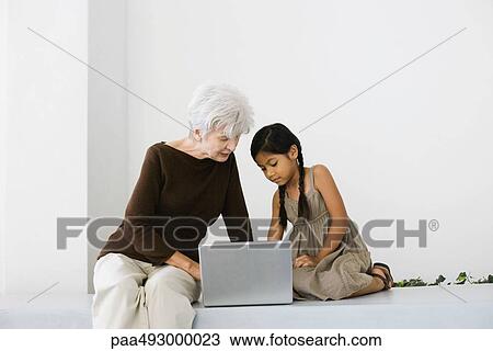 Senior woman and granddaughter using laptop together, looking down View Large Photo Image Stock Image - Senior woman and granddaughter using laptop together, looking down. Fotosearch