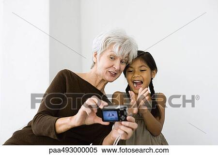 Senior woman photographing self and granddaughter with digital camera, both laughing View Large Photo Image Stock Photography - Senior woman photographing self and granddaughter with digital camera, both laughing. Fotosearch