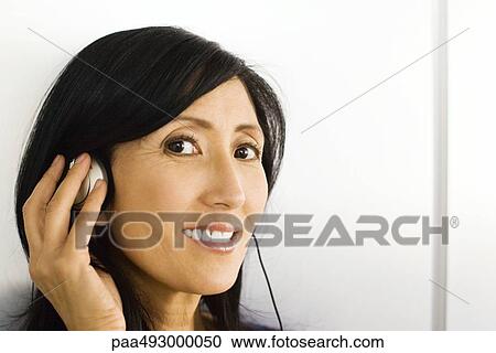 Woman listening to headphones, hand over ear, smiling at camera View Large Photo Image Stock Image - Woman listening to headphones, hand over ear, smiling at camera. Fotosearch