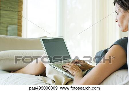 Woman reclining on sofa, using laptop computer View Large Photo Image Stock Photo - Woman reclining on sofa, using laptop computer. Fotosearch