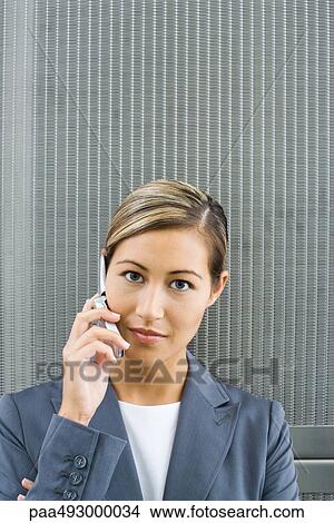 Woman using cell phone, looking at camera, portrait View Large Photo Image Picture - Woman using cell phone, looking at camera, portrait. Fotosearch