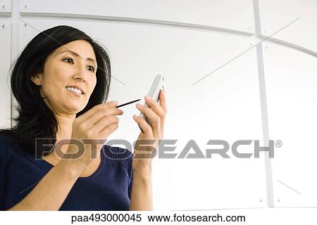 Woman using electronic organizer, smiling, low angle view View Large Photo Image Stock Photography - Woman using electronic organizer, smiling, low angle view. Fotosearch