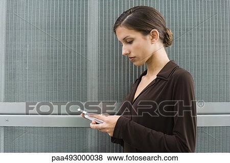 Young female looking down at cell phone, side view View Large Photo Image Stock Photo - Young female looking down at cell phone, side view. Fotosearch
