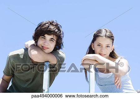 Brother and sister sitting sideways in chairs, leaning on elbows, smiling at camera View Large Photo Image Stock Photograph - Brother and sister sitting sideways in chairs, leaning on elbows, smiling at camera. Fotosearch
