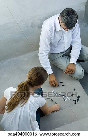 Stock Photography - Father and daughter playing dominoes, looking down, high angle view. Fotosearch