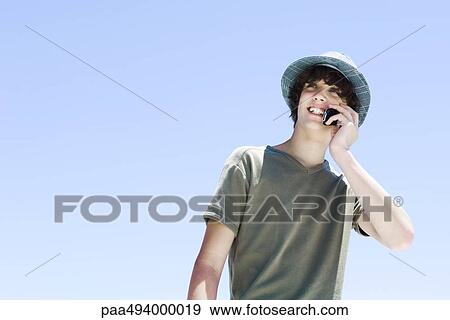 Teenage boy using cell phone, smiling, looking away View Large Photo Image Stock Photo - Teenage boy using cell phone, smiling, looking away. Fotosearch