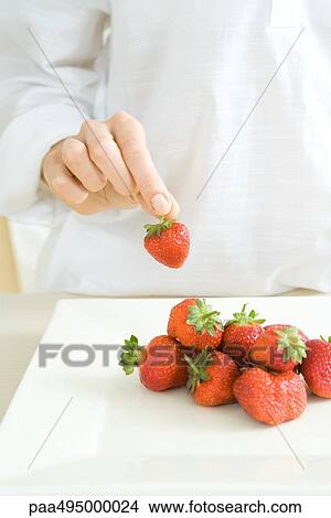 Hand picking up a strawberry from a pile on the counter View Large Photo Image Picture - Hand picking up a strawberry from a pile on the counter. Fotosearch