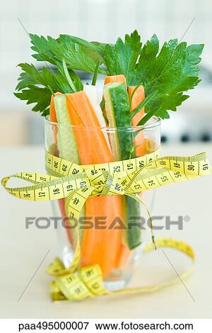 Measuring tape tied in a bow around a glass filled with fresh vegetables View Large Photo Image Stock Photo - Measuring tape tied in a bow around a glass filled with fresh vegetables. Fotosearch