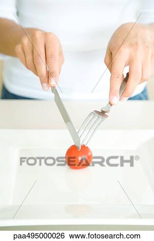 Woman cutting single cherry tomato with fork and knife, cropped view View Large Photo Image Stock Photograph - Woman cutting single cherry tomato with fork and knife, cropped view. Fotosearch