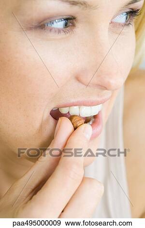 Woman eating a nut, looking away, headshot, portrait View Large Photo Image Stock Photo - Woman eating a nut, looking away, headshot, portrait. Fotosearch