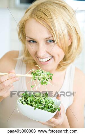 Woman eating radish sprouts with chopsticks, smiling at camera View Large Photo Image Stock Image - Woman eating radish sprouts with chopsticks, smiling at camera. Fotosearch