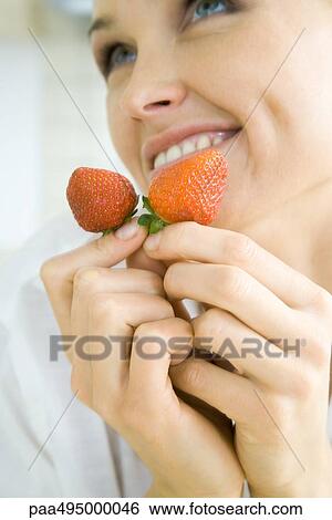 Woman holding a pair of strawberries, smiling, looking up, cropped View Large Photo Image Stock Photograph - Woman holding a pair of strawberries, smiling, looking up, cropped. Fotosearch