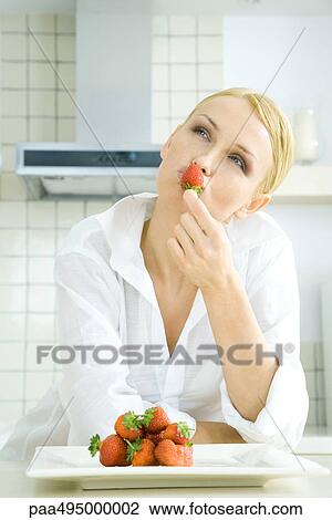 Woman holding strawberry to her lips, looking up, pile of strawberries on a plate View Large Photo Image Stock Image - Woman holding strawberry to her lips, looking up, pile of strawberries on a plate. Fotosearch
