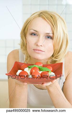 Woman holding up a plate of Caprese salad, looking at camera View Large Photo Image Stock Photography - Woman holding up a plate of Caprese salad, looking at camera. Fotosearch