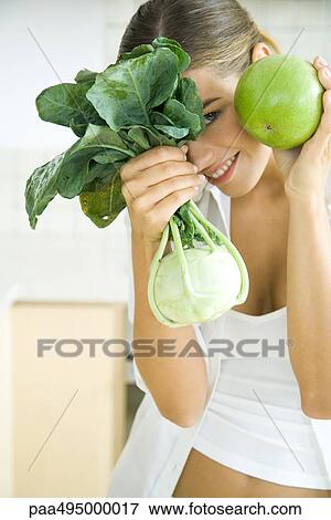 Woman holding up and hiding behind fresh kohlrabi and apple, smiling at camera View Large Photo Image Stock Photo - Woman holding up and hiding behind fresh kohlrabi and apple, smiling at camera. Fotosearch